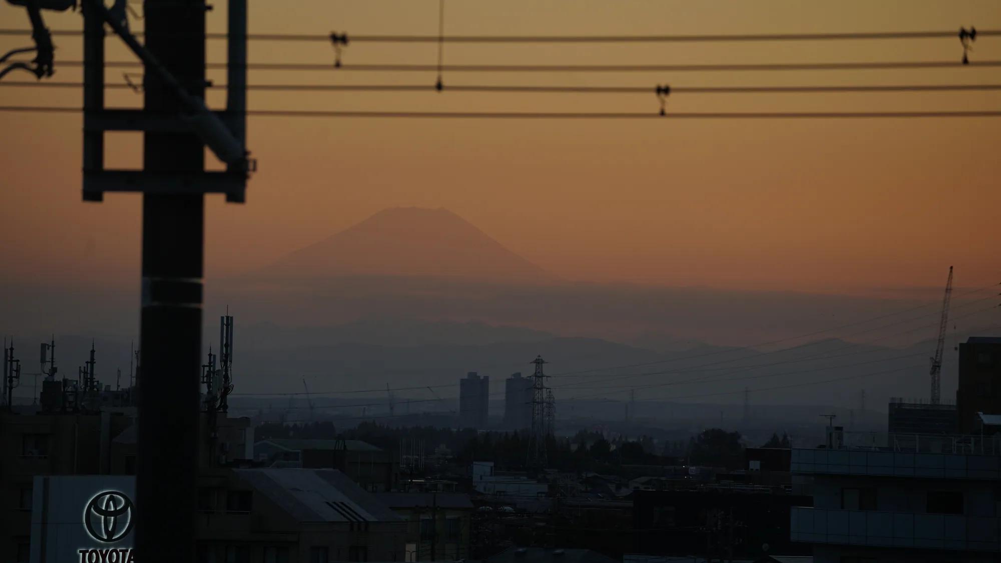 Silhouette des Fuji hinter Bahnleitungen im orangefarbenen Abendlicht