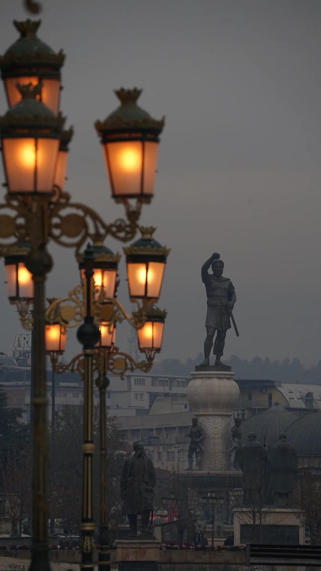 Leuchtende historische Laternen und ein Monument im dichten Nebel von Skopje