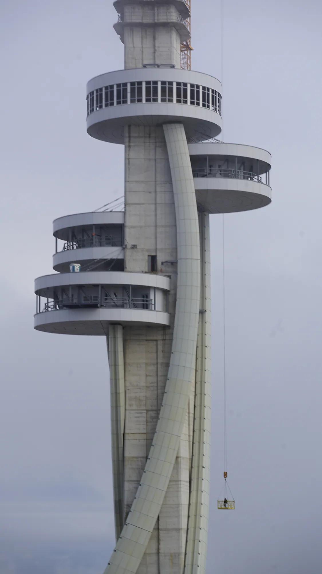 Betonturm mit umlaufenden Plattformen und einem schwebenden Baukorb